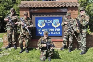 The Heathens reenactment group standing in front of the Welcome to Martlesham Heath Sign hanging at the entrance gate to the site.